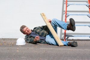 A worker falls off a ladder holding a plank of wood