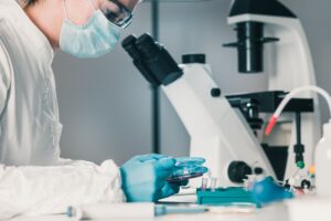 A medical professional looking down a microscope.