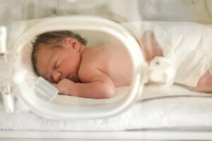 A baby with a brain injury laying in an incubator