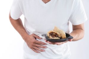 A man holding a plate and food and clutching his abdomen due to severe food poisoning