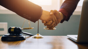 A solicitor and client shaking hands after discussing how to sue for assault at work compensation.