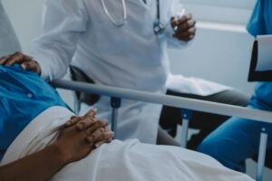 Two medical professionals stood around a patient in a hospital bed. 