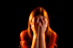 A blurry image of a woman holding her face in her hands