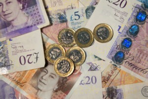 A pile of bank notes and pound coins to represent bank data breach compensation.