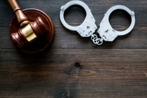 A gavel and a pair of handcuffs on a wooden table
