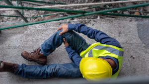 Construction worker holding knee after falling from a height. 