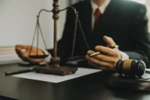 A solicitor sits at a desk with a contract, a wooden gavel and justice scales.